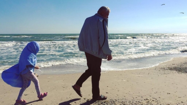 Дедушка и внучка у моря в холодный летний день